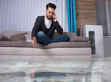 image of man on couch in flooded living room